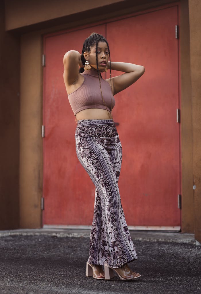 A fashionable woman poses confidently against a red door, highlighting her stylish outfit.