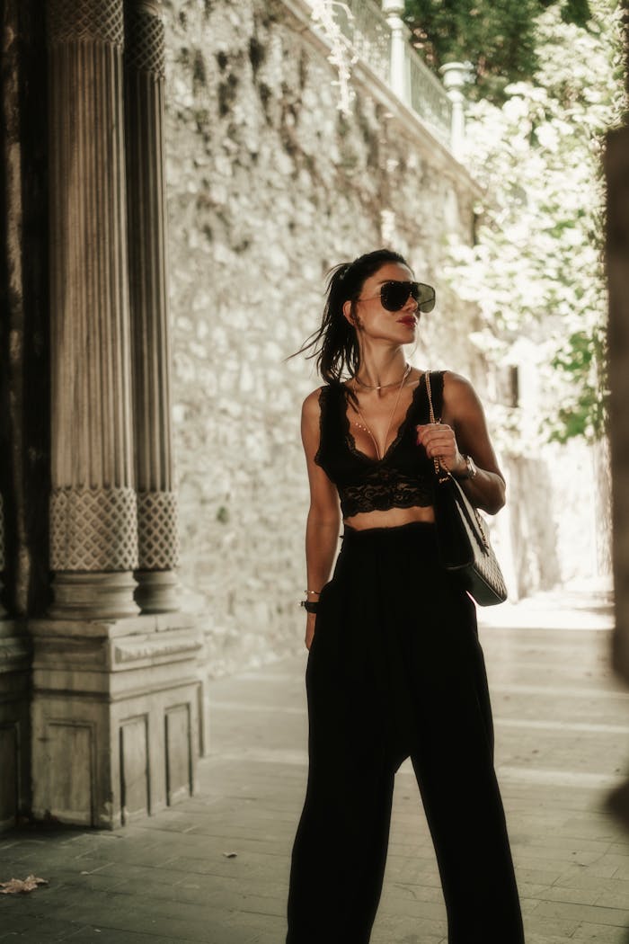 Stylish woman in urban setting wearing lace crop top and palazzo pants, exuding modern fashion.